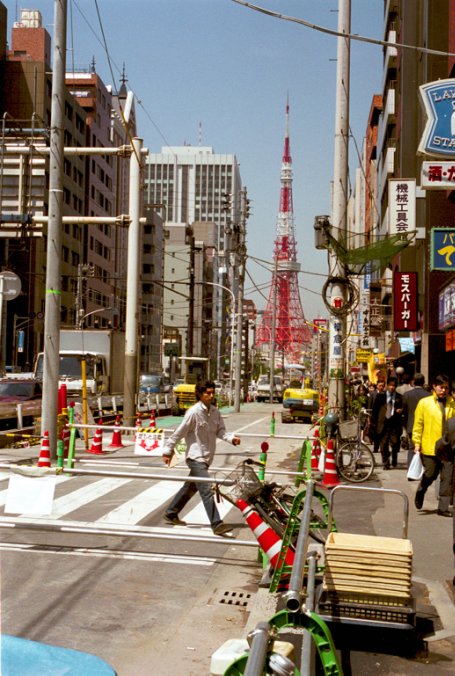 Tokyo Tower seens from one of the main streets, with people, cars, road works