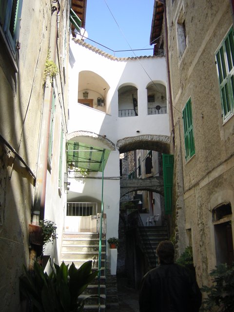 A renovated house with white walls, an arch being widened and reused as a corridor between two buildings. Isolabona, Italy